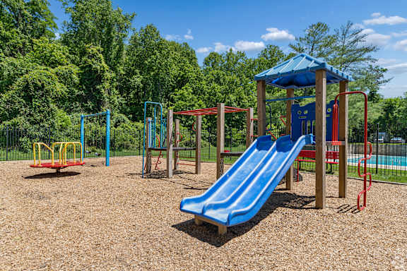 A playground with a blue slide and a red swing set.