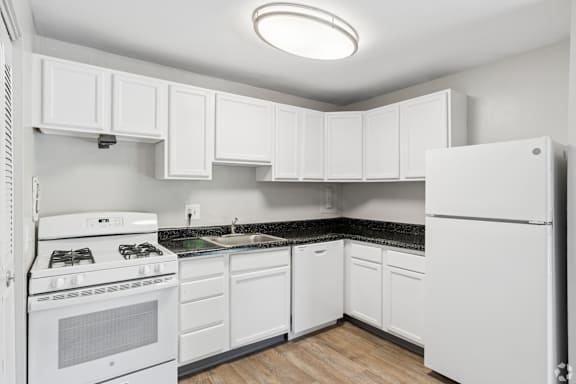 A white kitchen with a stove, refrigerator, and cabinets.