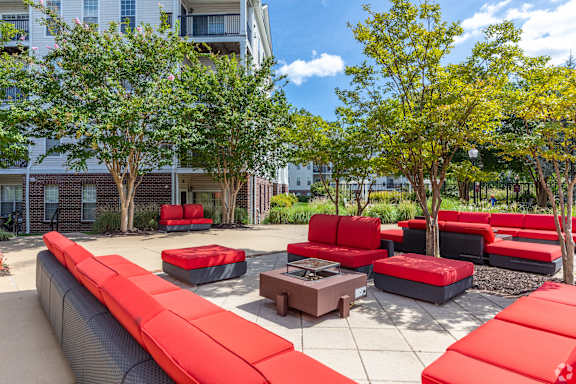 A red couch is in the middle of a courtyard.