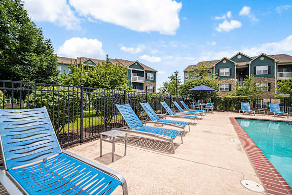 A pool area with sun loungers and a fence.