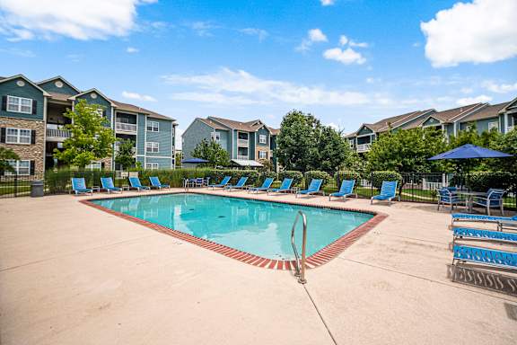 A swimming pool surrounded by blue lounge chairs and umbrellas.