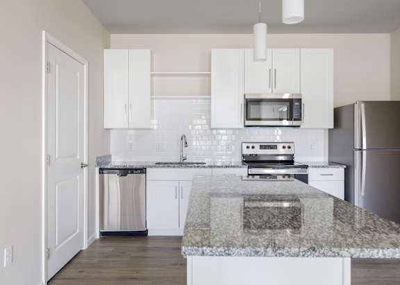 A kitchen with a granite countertop and white cabinets.