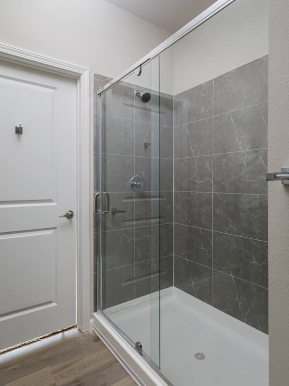 A white door is open to a bathroom with a glass shower stall.