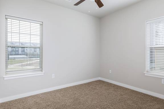 A room with a carpeted floor and a ceiling fan.