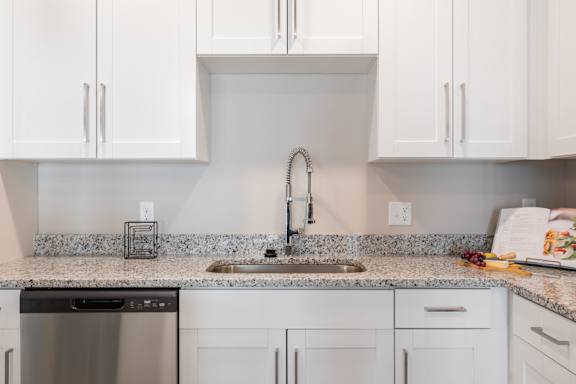 A kitchen with white cabinets and a granite countertop.