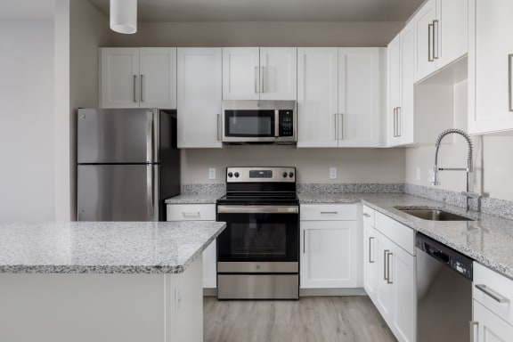 a kitchen with white cabinets and granite countertops  at The Edison at Tiffany Springs, Kansas City, MO, 64153