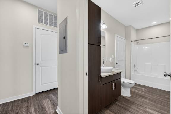 A bathroom with a white door, brown cabinet, and a white toilet.