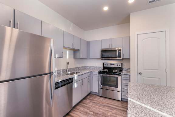 A kitchen with a stainless steel refrigerator and a stove top oven.