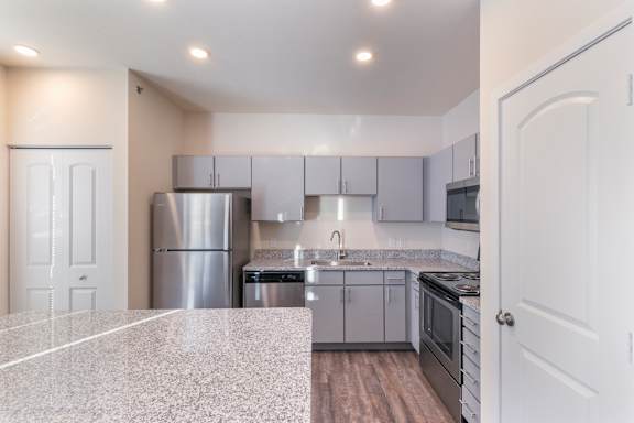 A kitchen with a granite countertop and stainless steel appliances.