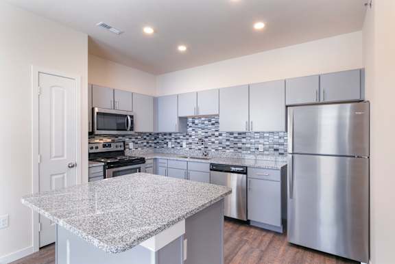 A kitchen with a granite countertop and stainless steel appliances.