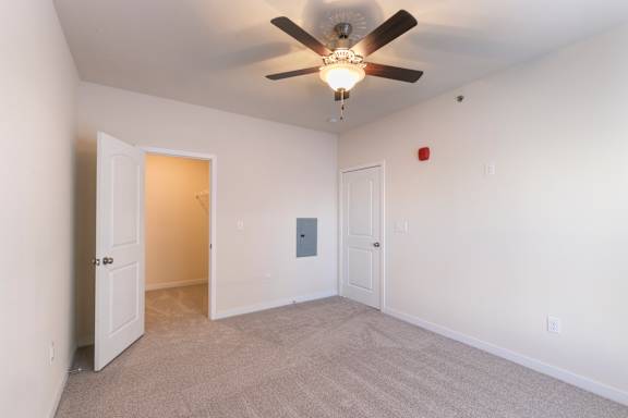 A room with a ceiling fan and two doors.