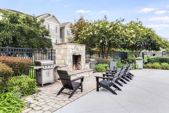 A patio with a fireplace, chairs, and a table.