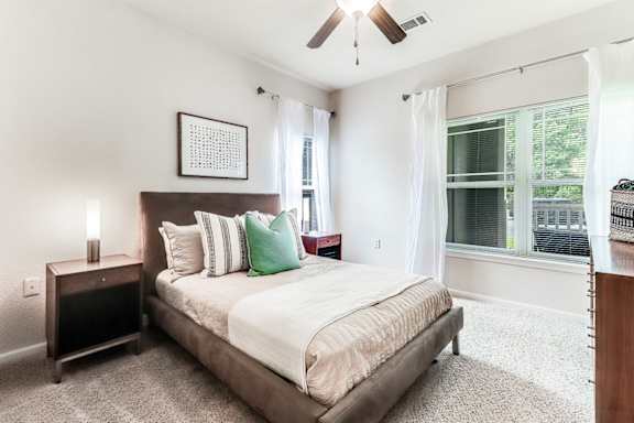 A bedroom with a bed, nightstand, and window.