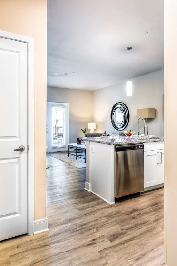 A kitchen with a white door and a round mirror on the wall.