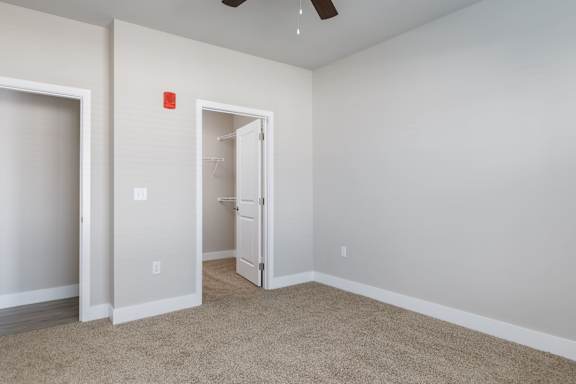 A room with a carpeted floor and a ceiling fan.