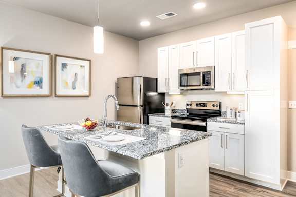 A kitchen with a granite countertop and white cabinets.