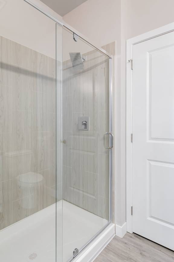 A white door is next to a glass shower stall.