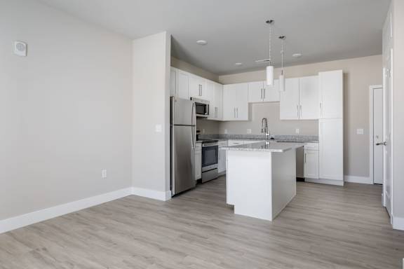 A modern kitchen with a white island and stainless steel appliances.