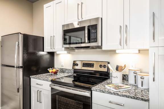A black refrigerator is next to a black microwave in a kitchen.