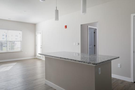 A kitchen island with a granite countertop and a door leading to another room.