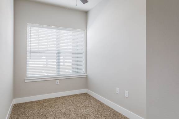 A room with a window covered by white blinds.