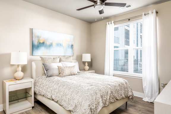 A bedroom with a large bed and a painting on the wall.