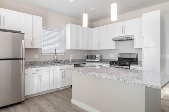 A modern kitchen with white cabinets and stainless steel appliances.