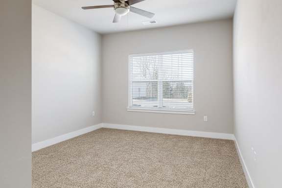 A room with a ceiling fan and a window with blinds.
