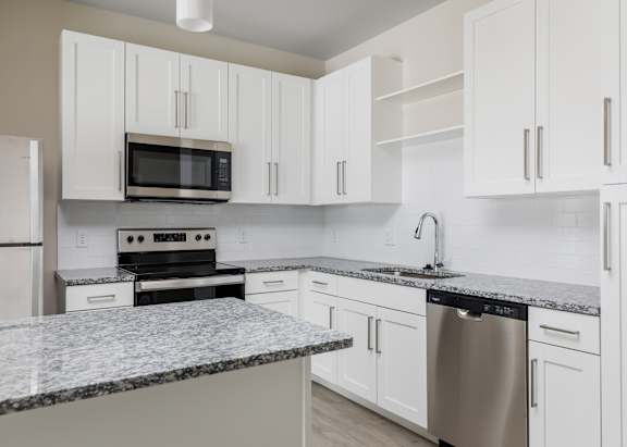 A kitchen with white cabinets and a granite countertop.