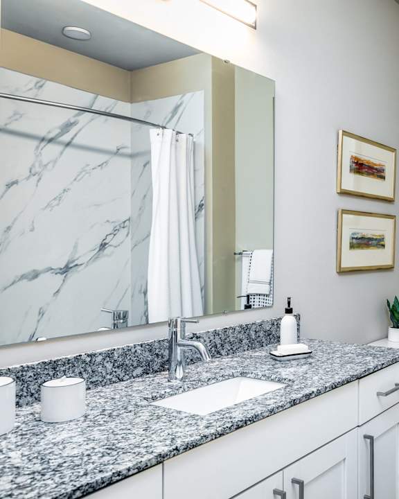 A bathroom with a marble countertop and a large mirror.