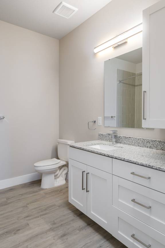 A white bathroom with a toilet, sink, and mirror.
