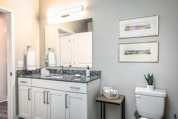 A bathroom with a toilet, sink, and two framed pictures on the wall.