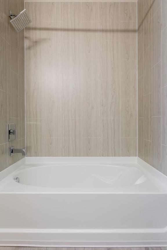 A white bathtub in a bathroom with a shower head above it.