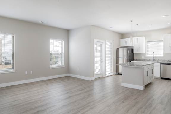 A spacious kitchen with a dining area and a view of the outdoors through the windows.