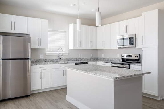A modern kitchen with white cabinets and a marble island.