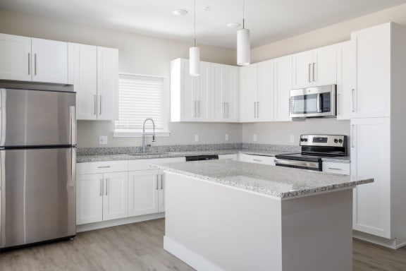 a kitchen with white cabinets and gray countertops  at The Edison at Tiffany Springs, Kansas City, MO