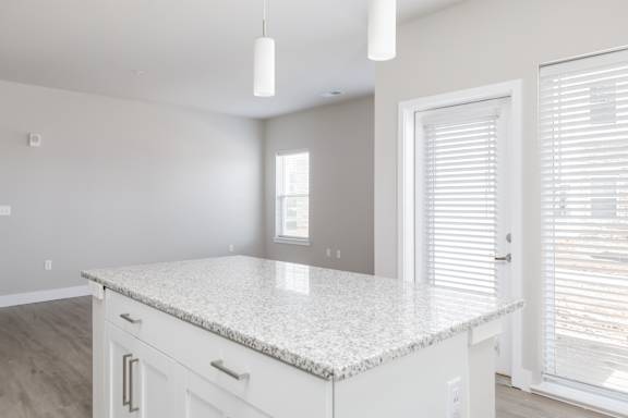 A kitchen with a granite countertop and white cabinets.