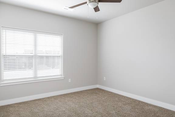A room with a ceiling fan and a window with blinds.