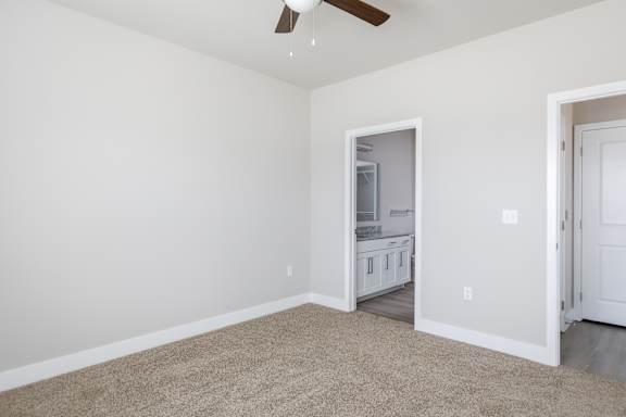A room with a ceiling fan and a doorway leading to another room.