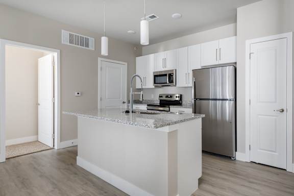 A kitchen with a white island and stainless steel appliances.
