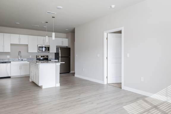 A kitchen with white cabinets and a wooden floor.