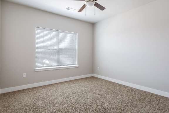 A room with a ceiling fan and a window with blinds.