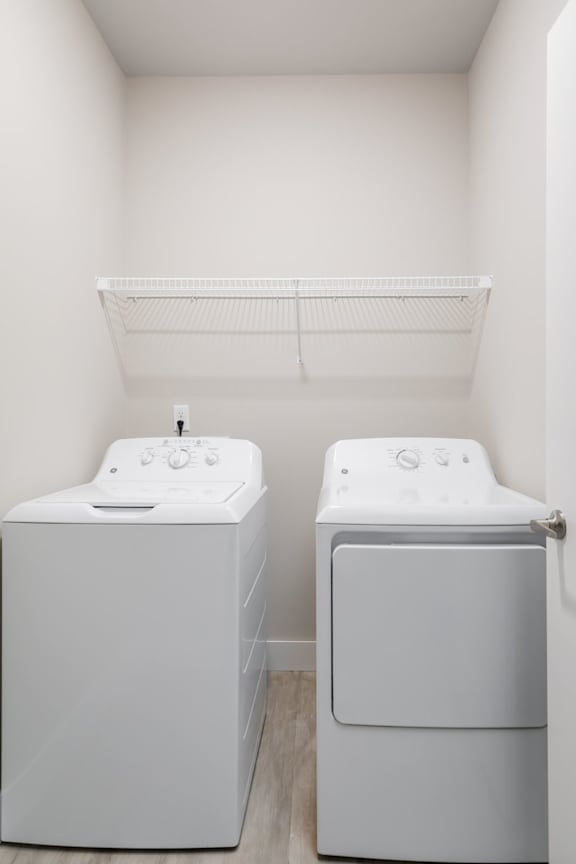 Two white front loading washing machines in a small laundry room.