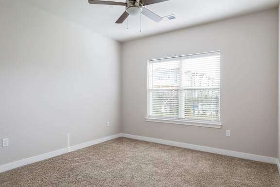A room with a ceiling fan and a window with blinds.