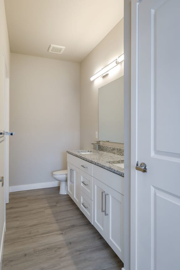 A bathroom with a toilet, sink, and mirror.