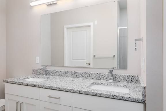 A bathroom with a granite countertop and a white door.