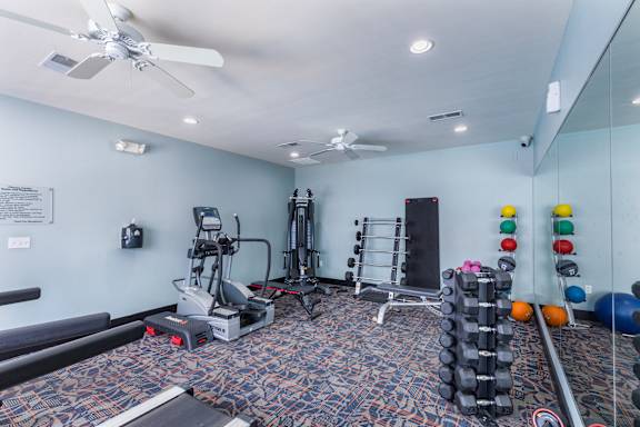 A gym room with a variety of equipment including weights and a treadmill.