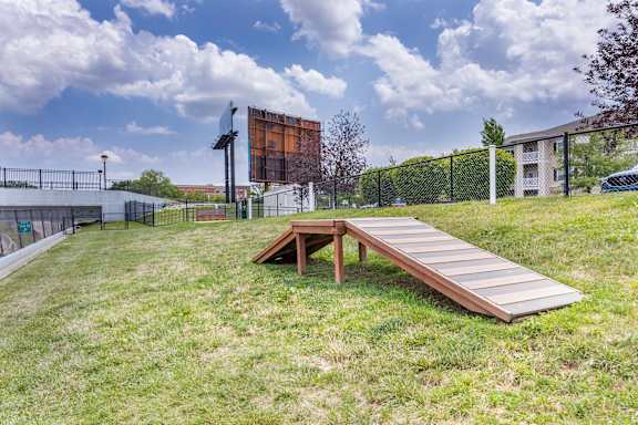 A wooden ramp leads to a picnic table in a grassy area.