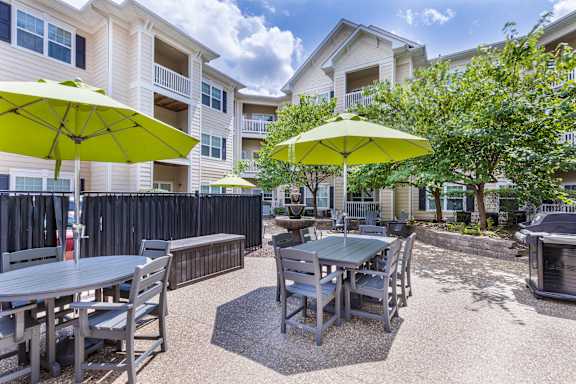 A patio with a table and chairs and umbrellas.