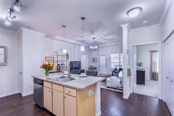 A kitchen with a sink, cabinets, and a counter.